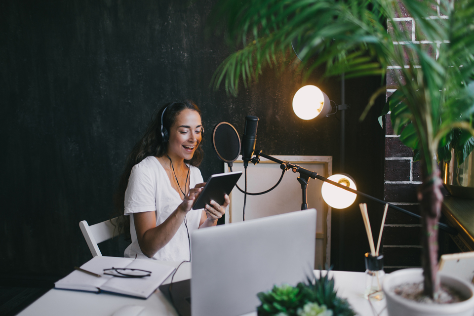 Woman sitting at microphone recording a podcast